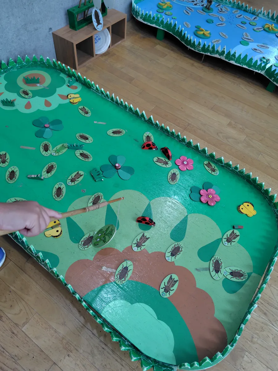 緑の盤の上に置かれた、木で作られた虫のおもちゃ